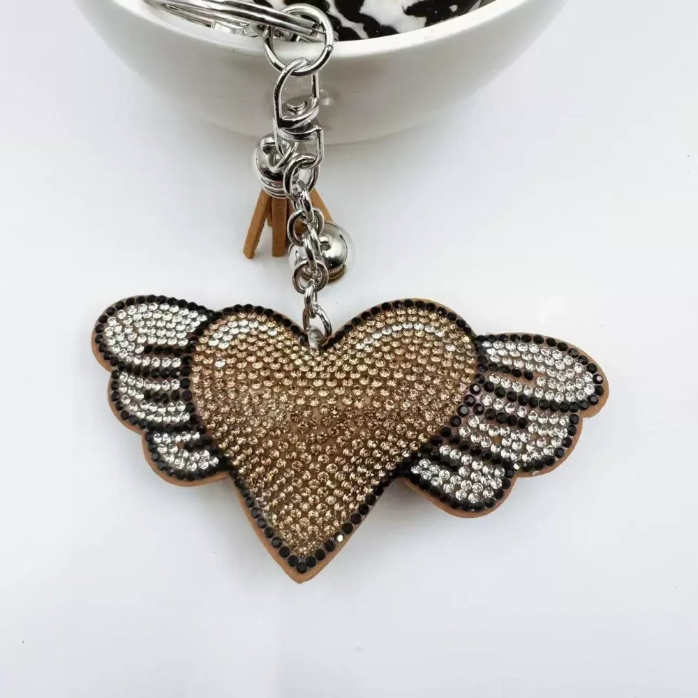 Purple and pink winged heart rhinestone charm beads with tassels, bells, and silver key rings on a white background - Khaki