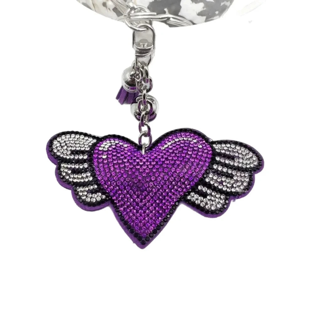 Purple and pink winged heart rhinestone charm beads with tassels, bells, and silver key rings on a white background - Purple
