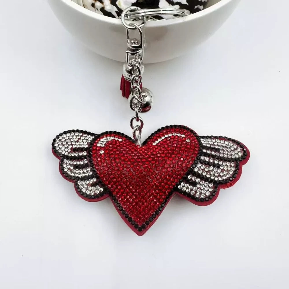 Purple and pink winged heart rhinestone charm beads with tassels, bells, and silver key rings on a white background - Red