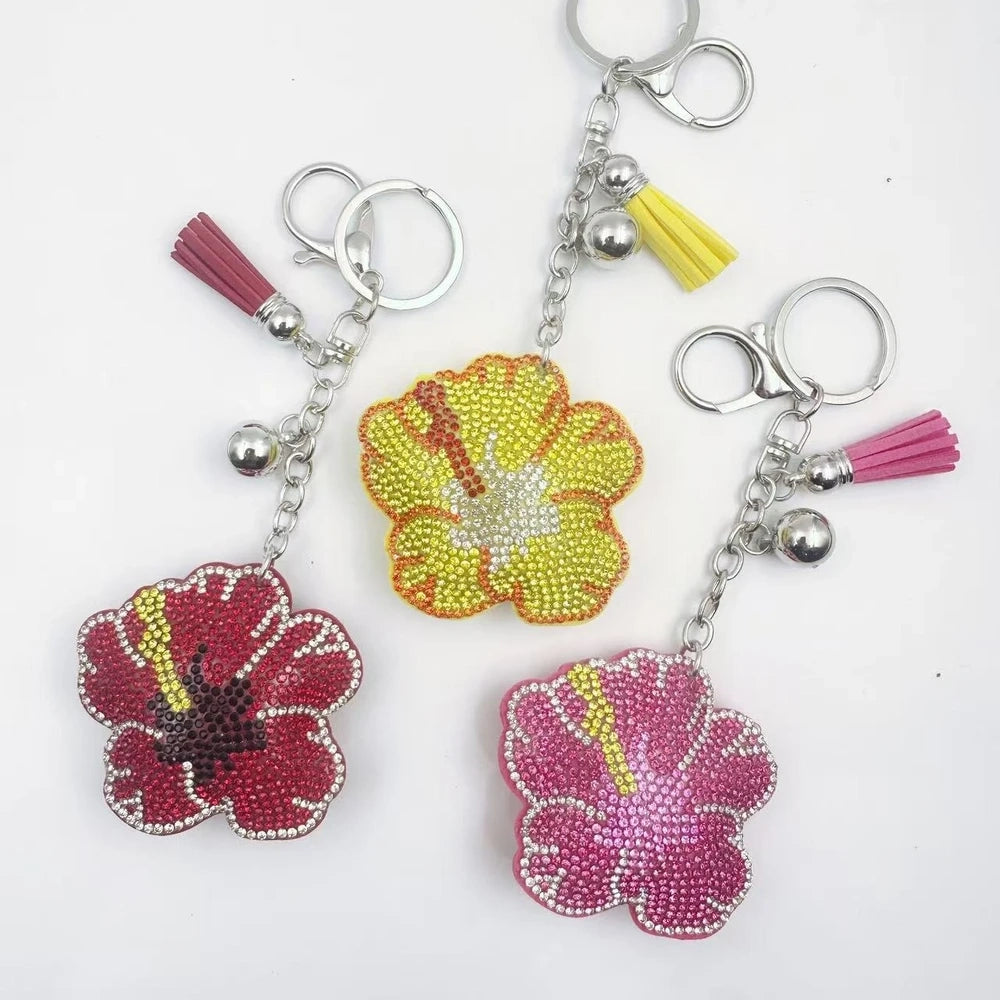 Three large rhinestone hibiscus flower silicone focal beads displayed as silver keychains in yellow, pink, and red.