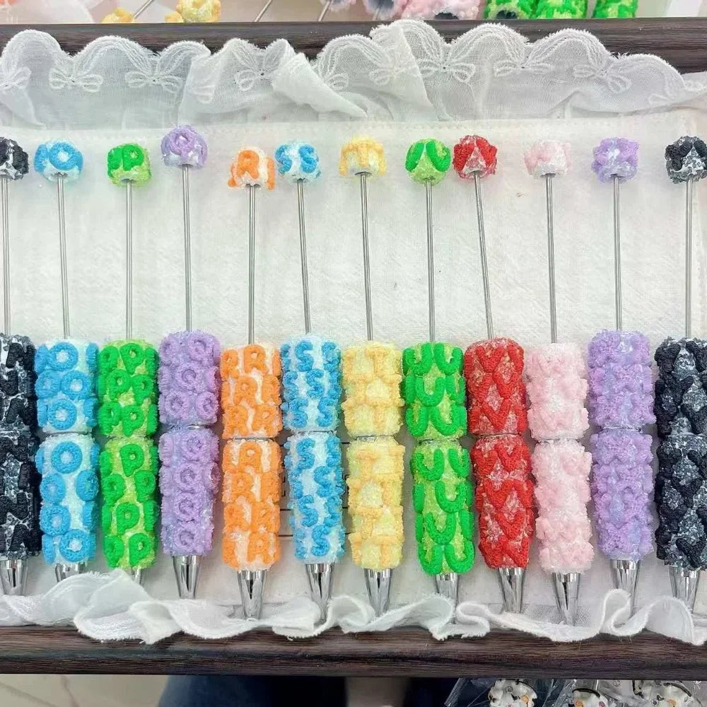 Colorful fuzzy letter clay beadable pens in blue, green, purple, orange, yellow, red, pink and black displayed on a white surface at DIY Mini Planet
