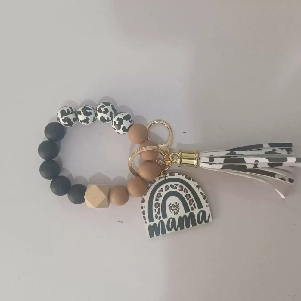 Set of 8 Mama rainbow leopard print silicone bead wristlet keychains with leather tassels and heart charm pendants in assorted colors including black, blue, yellow, green, pink, red, and purple on white background. - Coffee