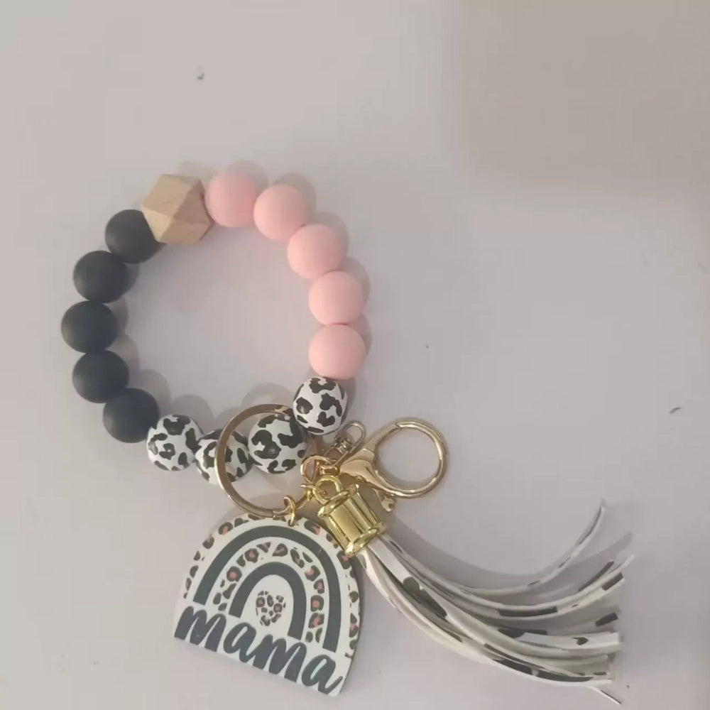 Set of 8 Mama rainbow leopard print silicone bead wristlet keychains with leather tassels and heart charm pendants in assorted colors including black, blue, yellow, green, pink, red, and purple on white background. - Pink-2