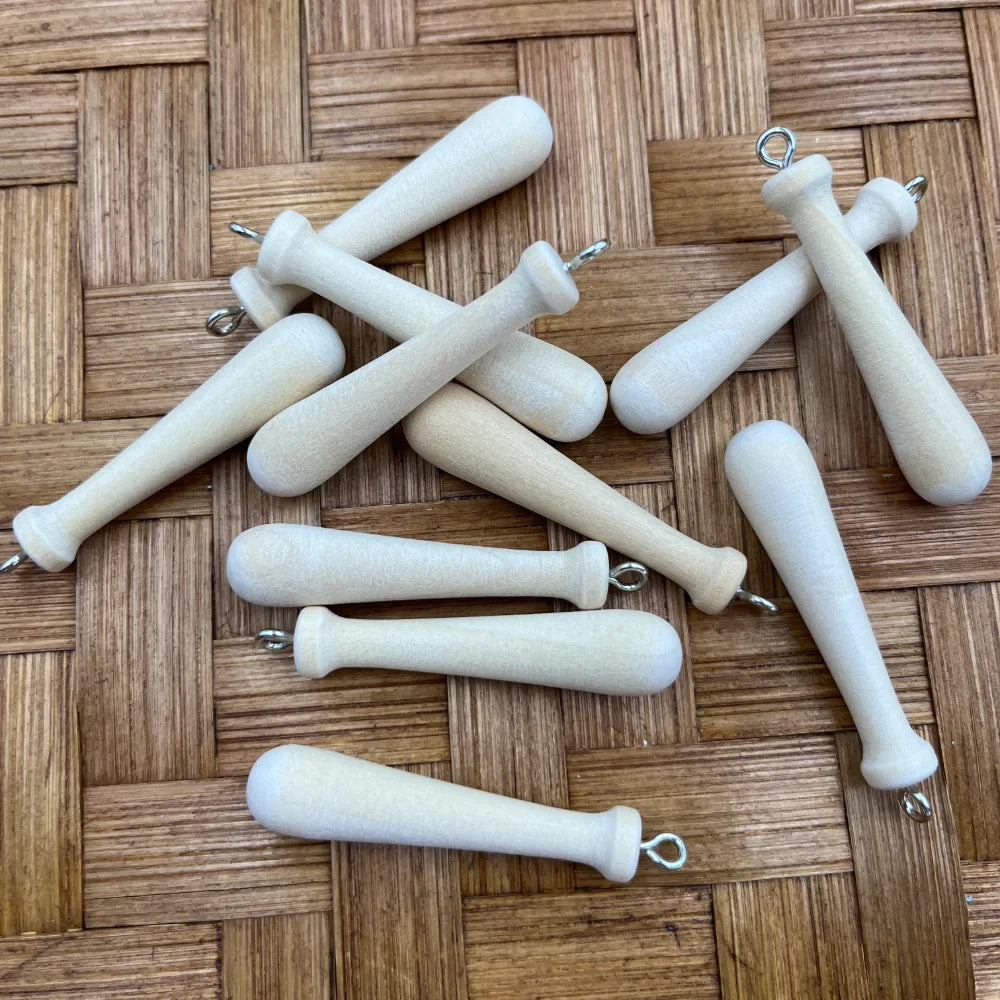 Mini baseball bat shaped acrylic bead charms with silver eye screw loops in natural unfinished wood-look finish, scattered on a wicker surface, perfect for beadable pens and keychains.