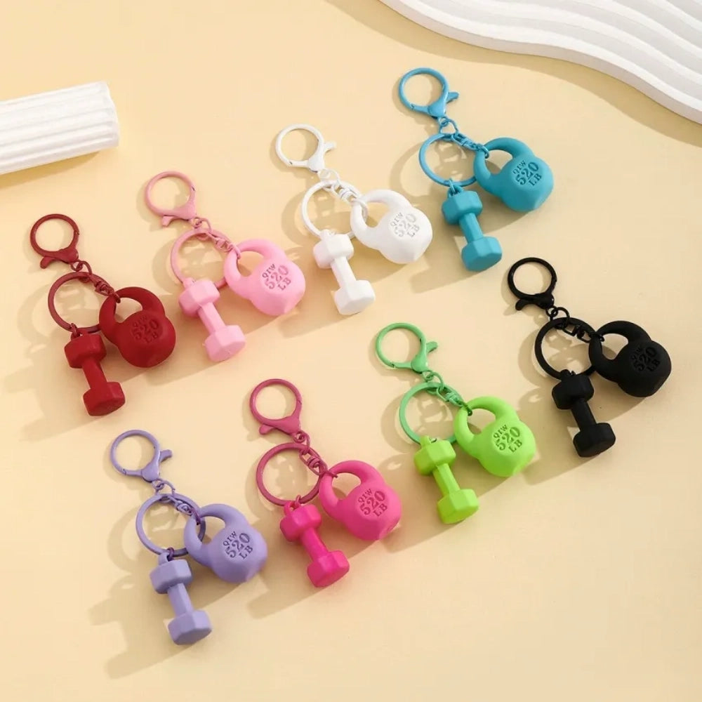 Set of colorful mini dumbbell and kettlebell keychain charms in red, pink, white, blue, black, purple, hot pink, and green, featuring 520 LB design, displayed on a yellow background.