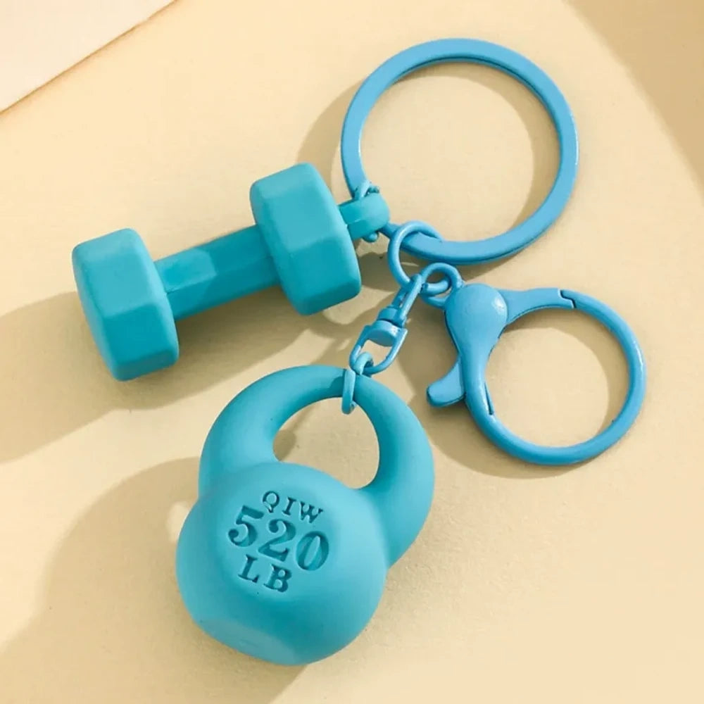 Set of colorful mini dumbbell and kettlebell keychain charms in red, pink, white, blue, black, purple, hot pink, and green, featuring 520 LB design, displayed on a yellow background. - Blue