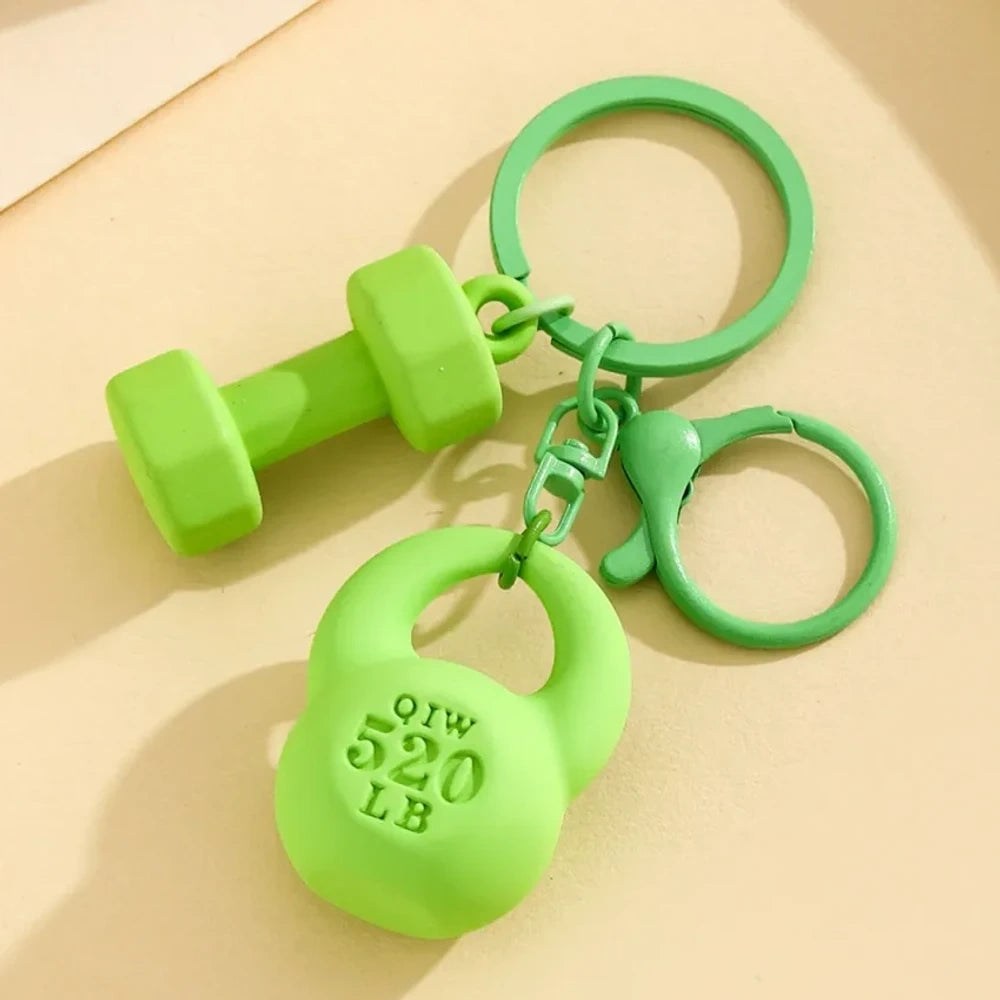 Set of colorful mini dumbbell and kettlebell keychain charms in red, pink, white, blue, black, purple, hot pink, and green, featuring 520 LB design, displayed on a yellow background. - Green