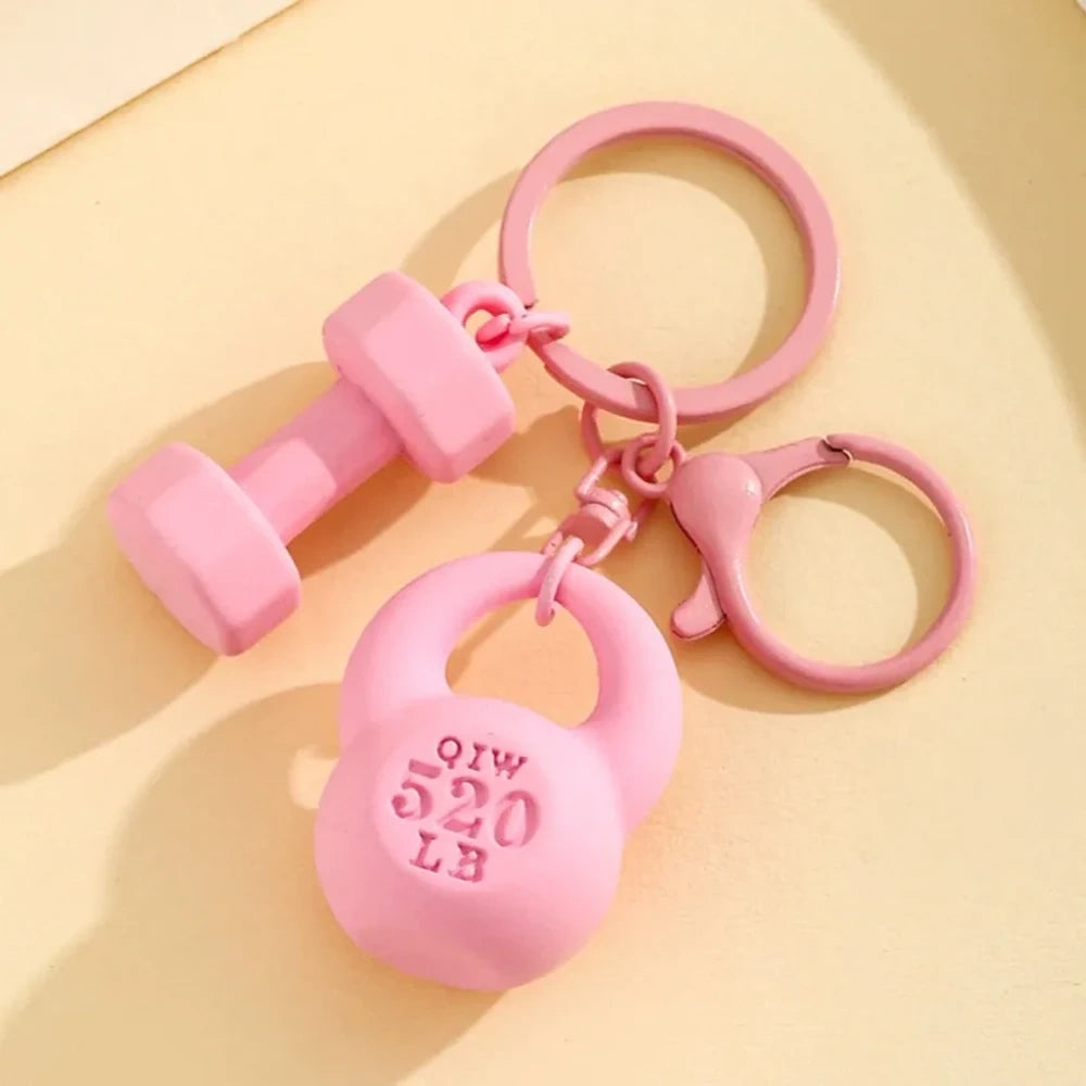 Set of colorful mini dumbbell and kettlebell keychain charms in red, pink, white, blue, black, purple, hot pink, and green, featuring 520 LB design, displayed on a yellow background. - Pink