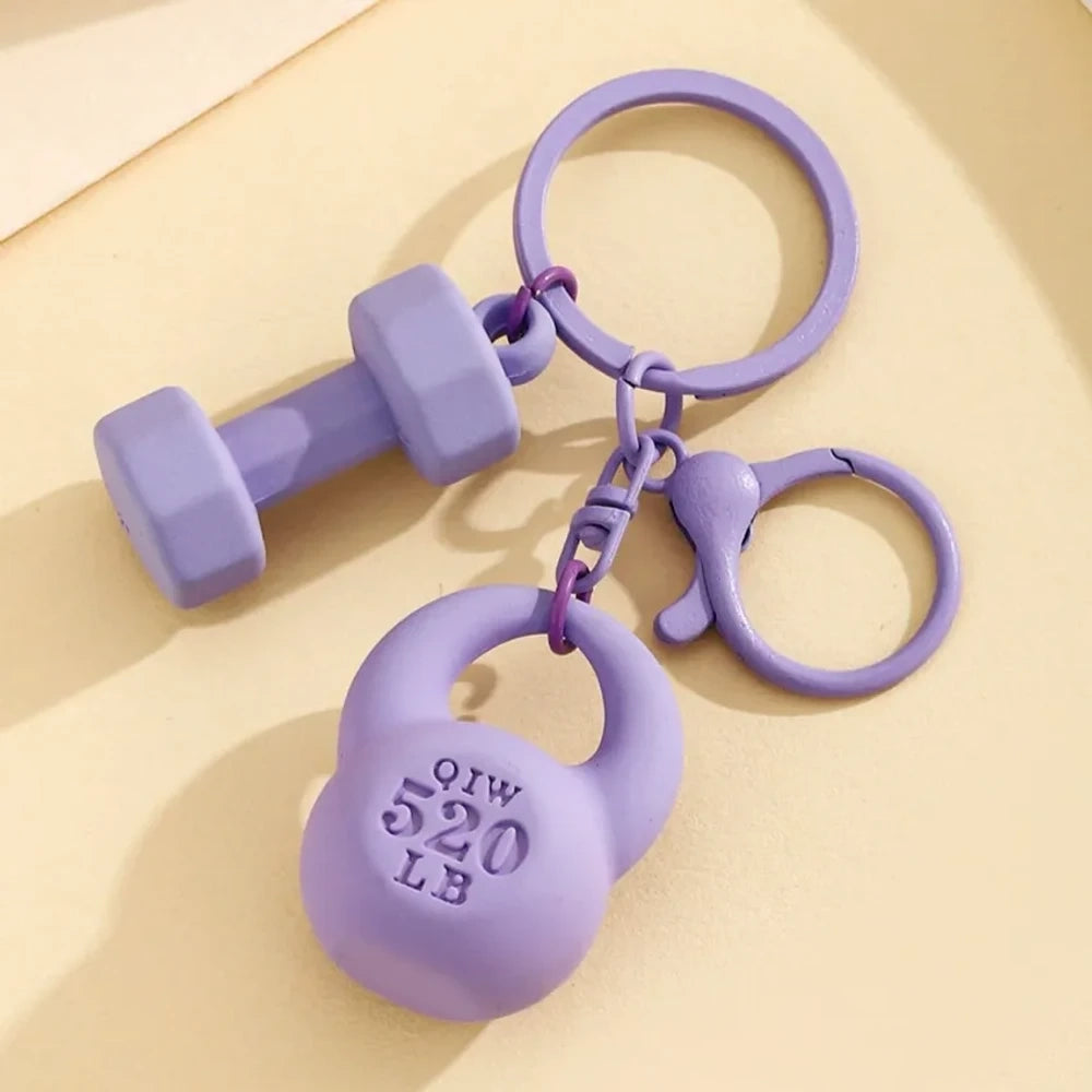Set of colorful mini dumbbell and kettlebell keychain charms in red, pink, white, blue, black, purple, hot pink, and green, featuring 520 LB design, displayed on a yellow background. - Purple