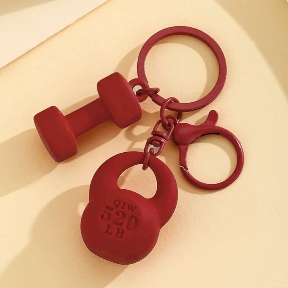 Set of colorful mini dumbbell and kettlebell keychain charms in red, pink, white, blue, black, purple, hot pink, and green, featuring 520 LB design, displayed on a yellow background. - Red