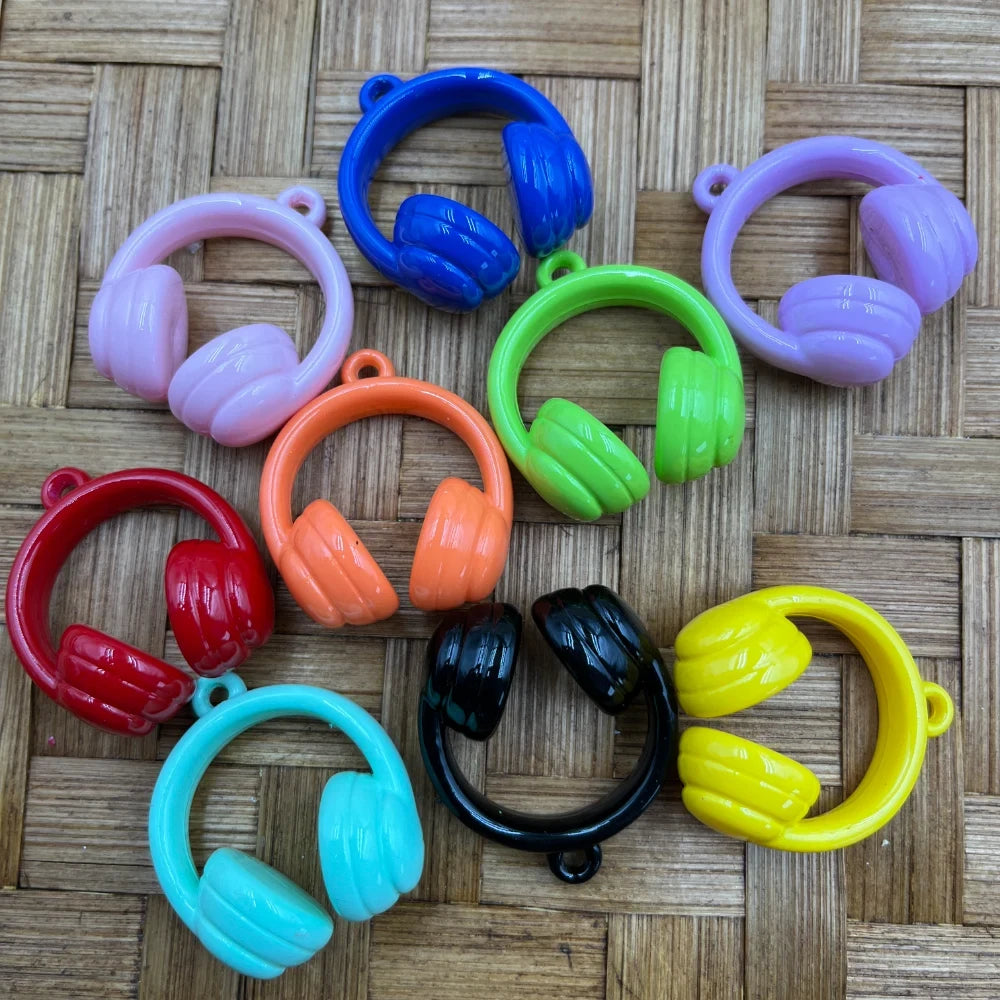 Ten colorful mini headphones acrylic bead charms in pink, blue, purple, green, orange, red, teal, black, and yellow arranged on a wicker surface.