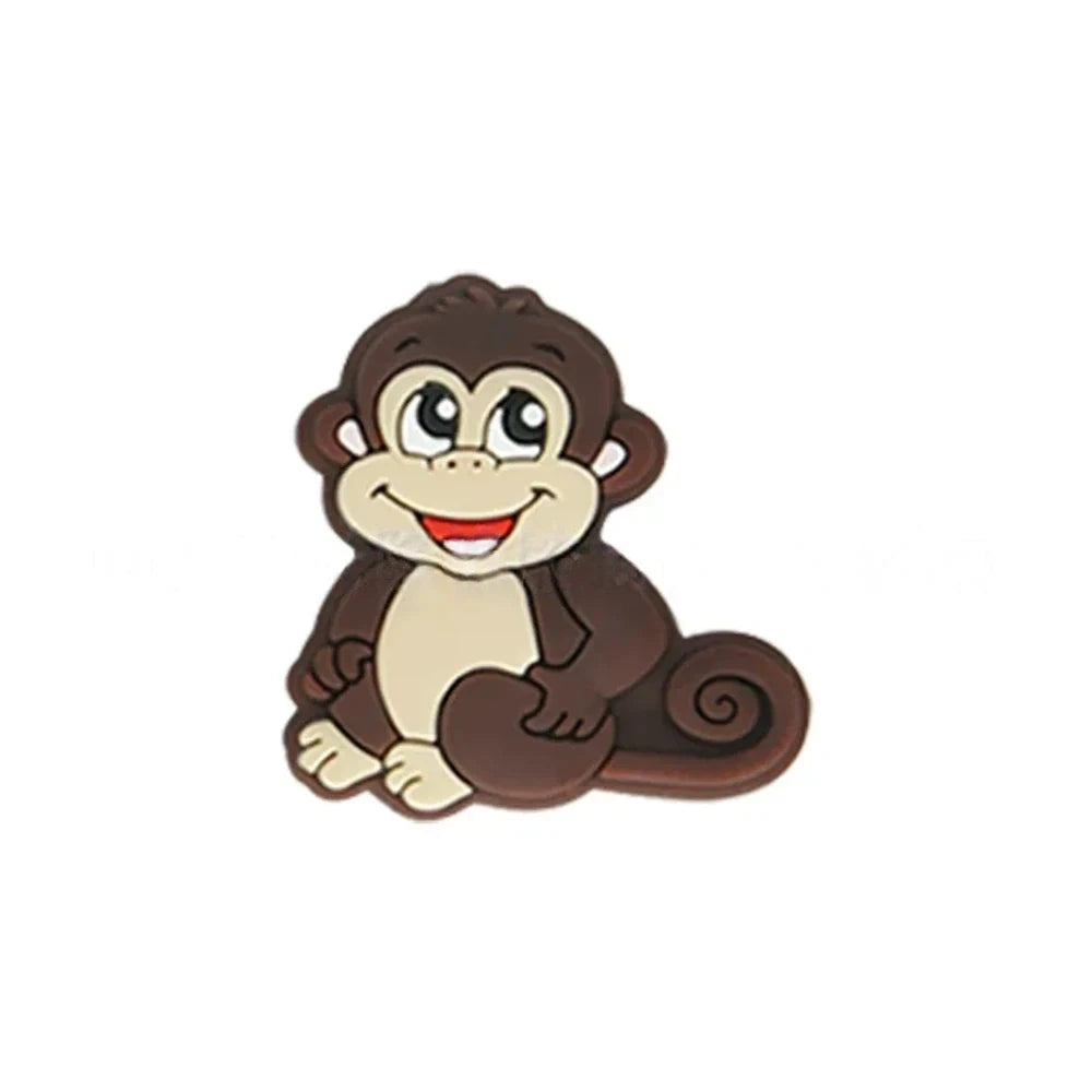 Seven colorful cartoon monkey silicone focal beads in brown, tan, grey, yellow, pink, blue, and purple displayed on a miniature white bench against a pink background. - Coffee