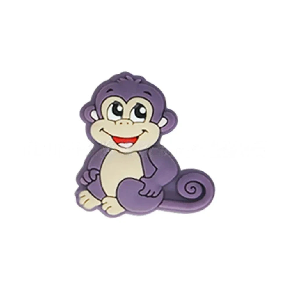 Seven colorful cartoon monkey silicone focal beads in brown, tan, grey, yellow, pink, blue, and purple displayed on a miniature white bench against a pink background. - Purple