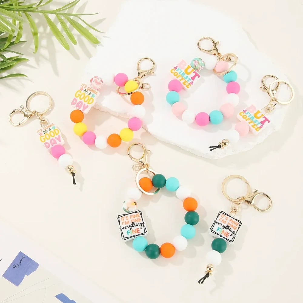 Colorful motivational quote printed silicone beads in pink, orange, teal, yellow and white used on beaded keychain bracelets with gold lobster clasp hardware