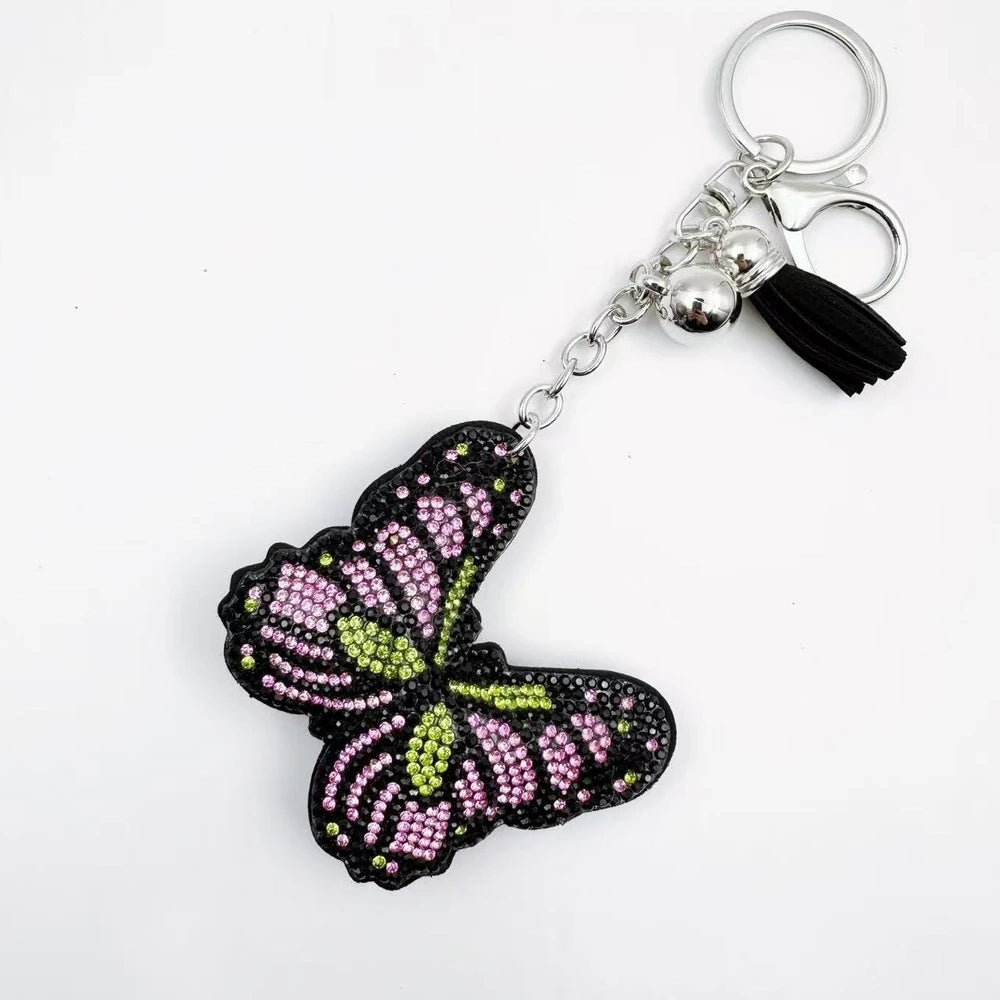Two butterfly rhinestone fancy bead charms with black backing, pink accents, silver hardware, and tassels on a white background. - 1