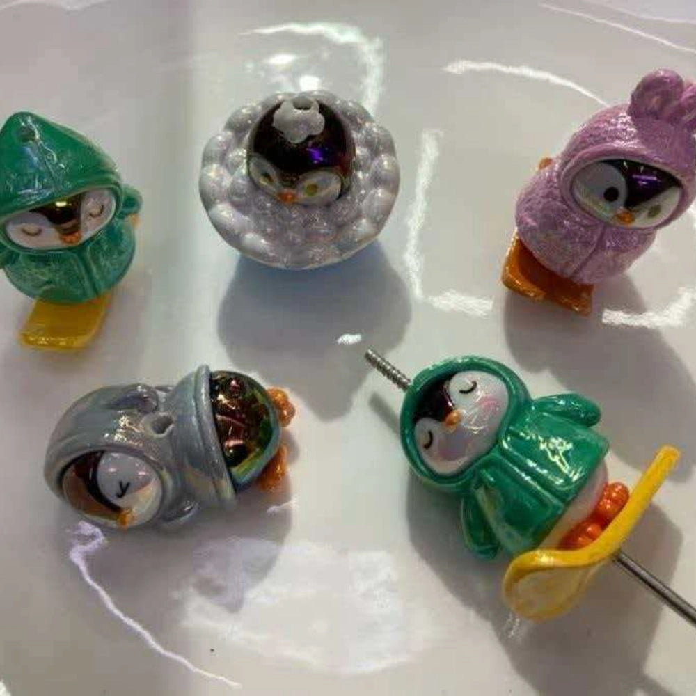 Assorted 3D hooded penguin resin straw toppers in green, white, pink, and gray with glossy finish