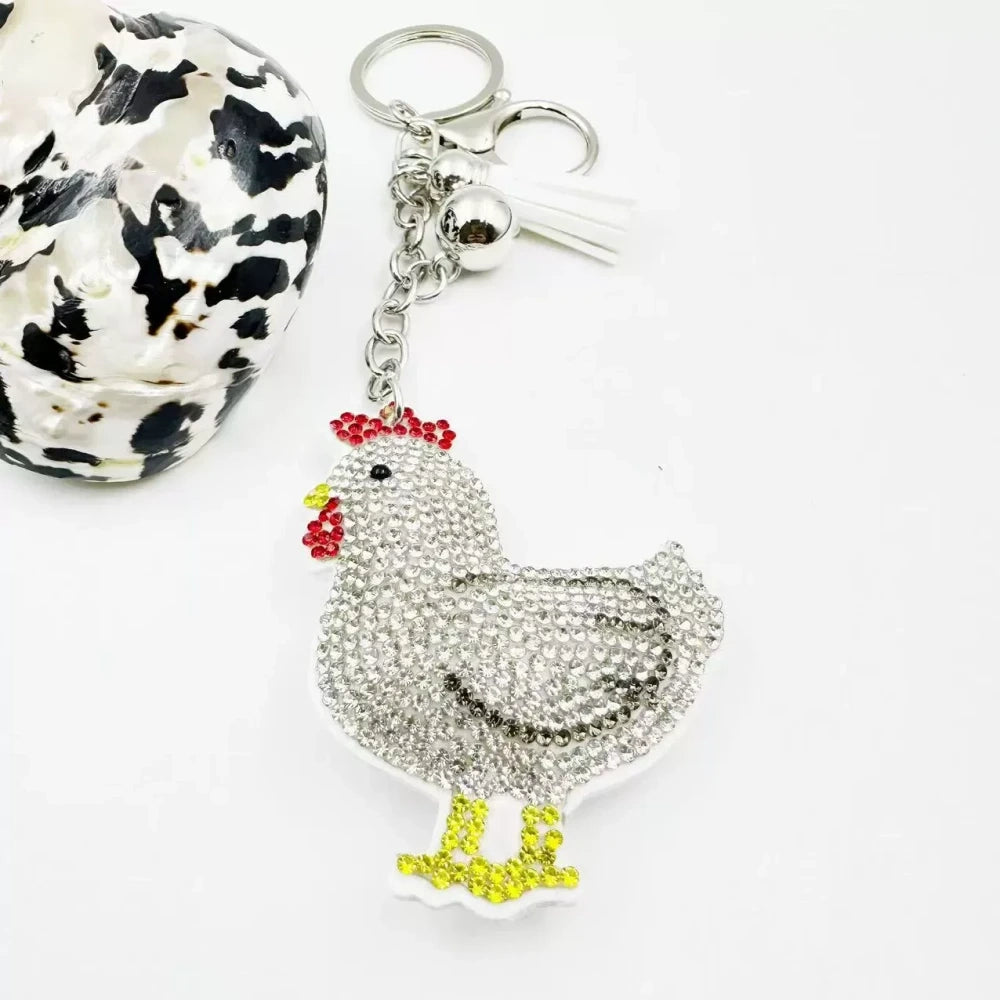 Two white hen rhinestone fancy bead charms with silver keychain rings and tassel accents on white background - White