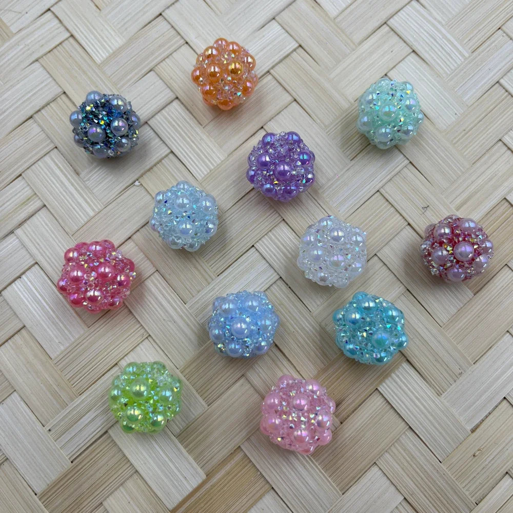11 pastel iridescent crystal cluster berry beads in assorted colors including pink, purple, blue, green, orange, and teal displayed on a woven bamboo surface