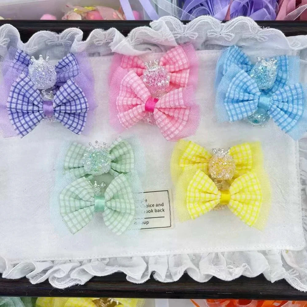Set of 5 pastel plaid gingham fabric bow hair clips with sparkling crown bead centers in purple, pink, blue, mint green, and yellow, displayed on a white lace-trimmed tray.
