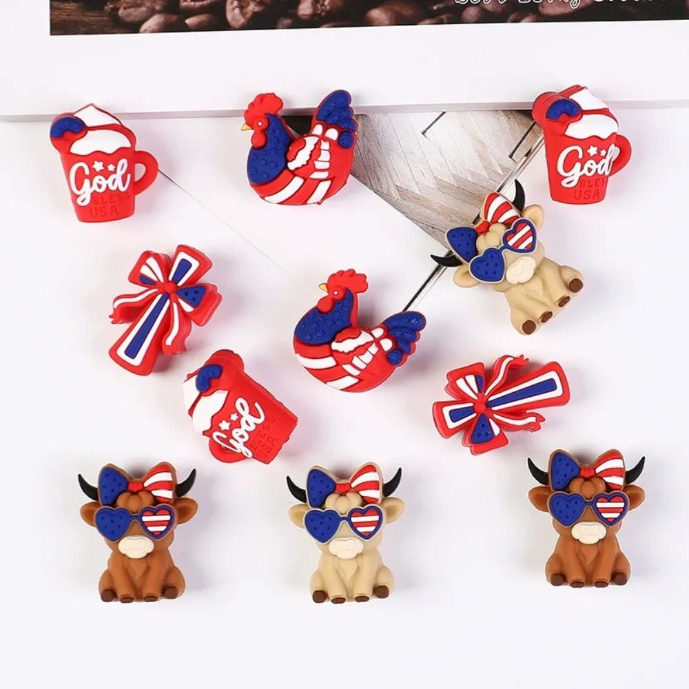 Patriotic God Bless USA silicone focal beads in red, white, and blue featuring roosters, highland cows with heart sunglasses, bows, and coffee mugs on a white background.