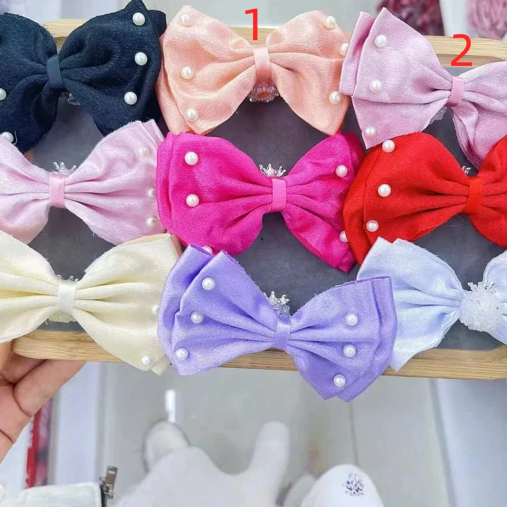 Assorted pearl-embellished velvet fabric bow appliques in multiple colors including pink, lavender, red, purple, navy, and white, displayed on a wooden rack for DIY crafts and accessories.