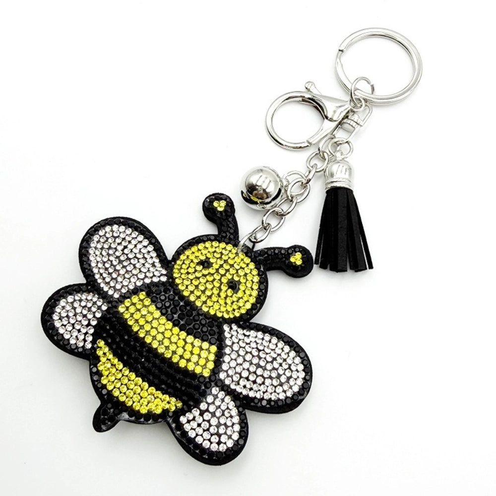 Sparkling rhinestone bumble bee keychain charm with yellow and clear crystals, silver bell, black tassel, and lobster clasp on white background.