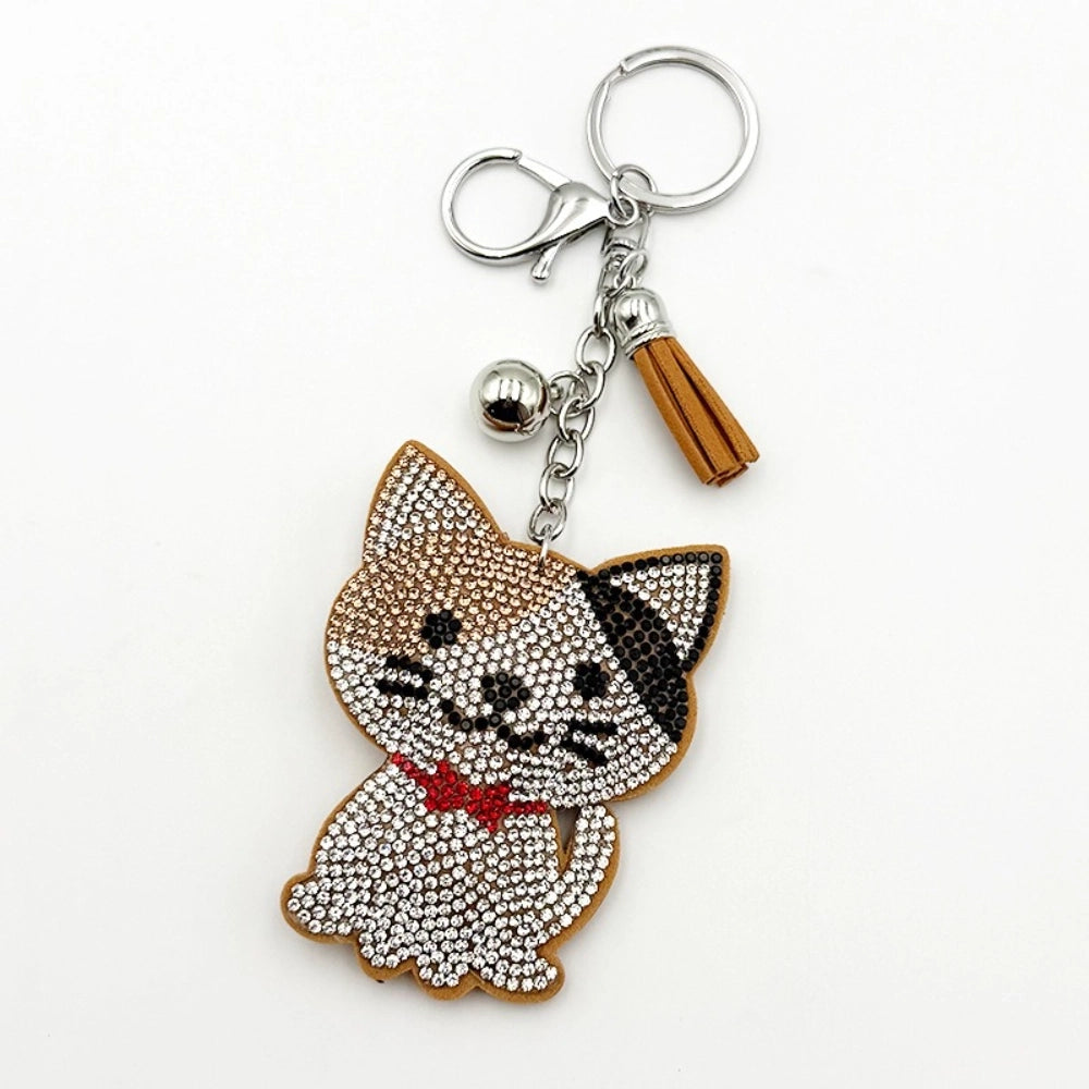 Crystal rhinestone cat keychain charm with red bow tie, brown tassel, silver bell, and lobster clasp on white background
