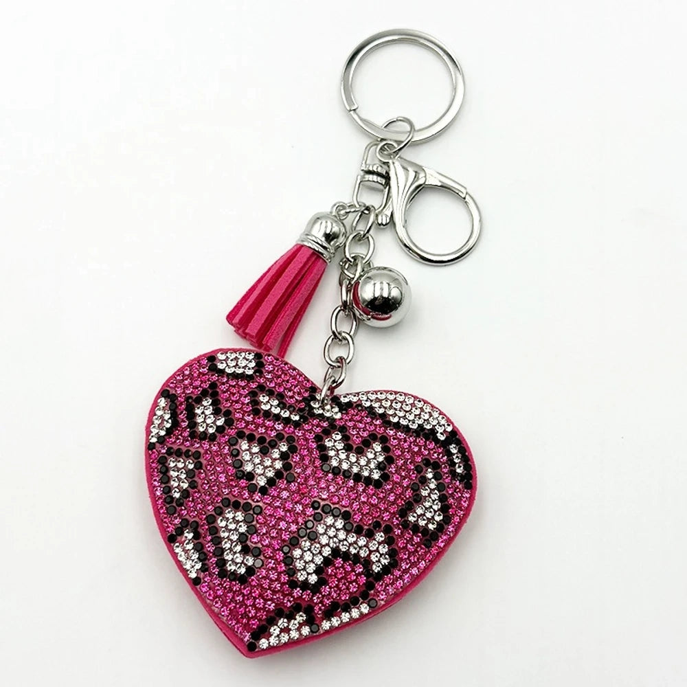 Four rhinestone crystal leopard print heart-shaped keychain charms in pink, purple, brown, and black with silver tassel and bell accents on white background. - Rose Red