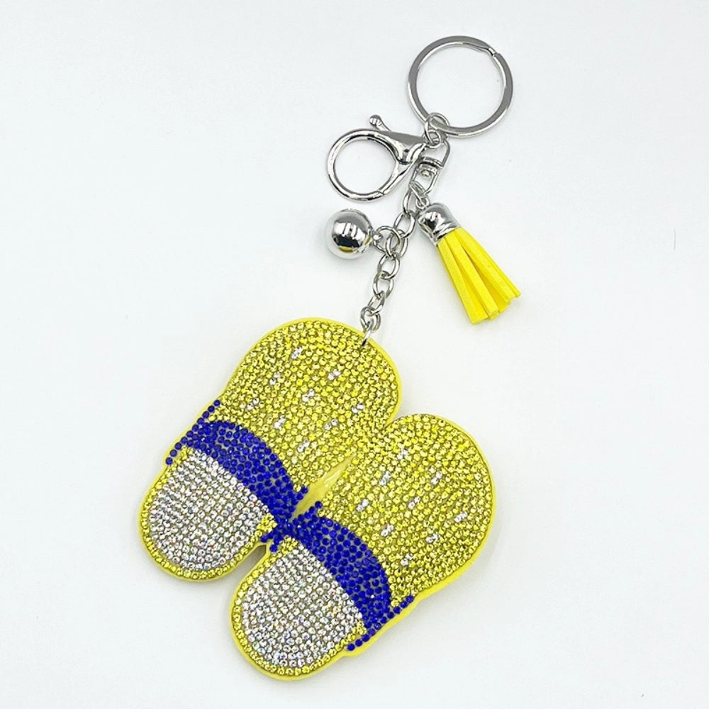Yellow and blue rhinestone crystal flip flop slipper keychain charm with yellow tassel and silver hardware on white background.