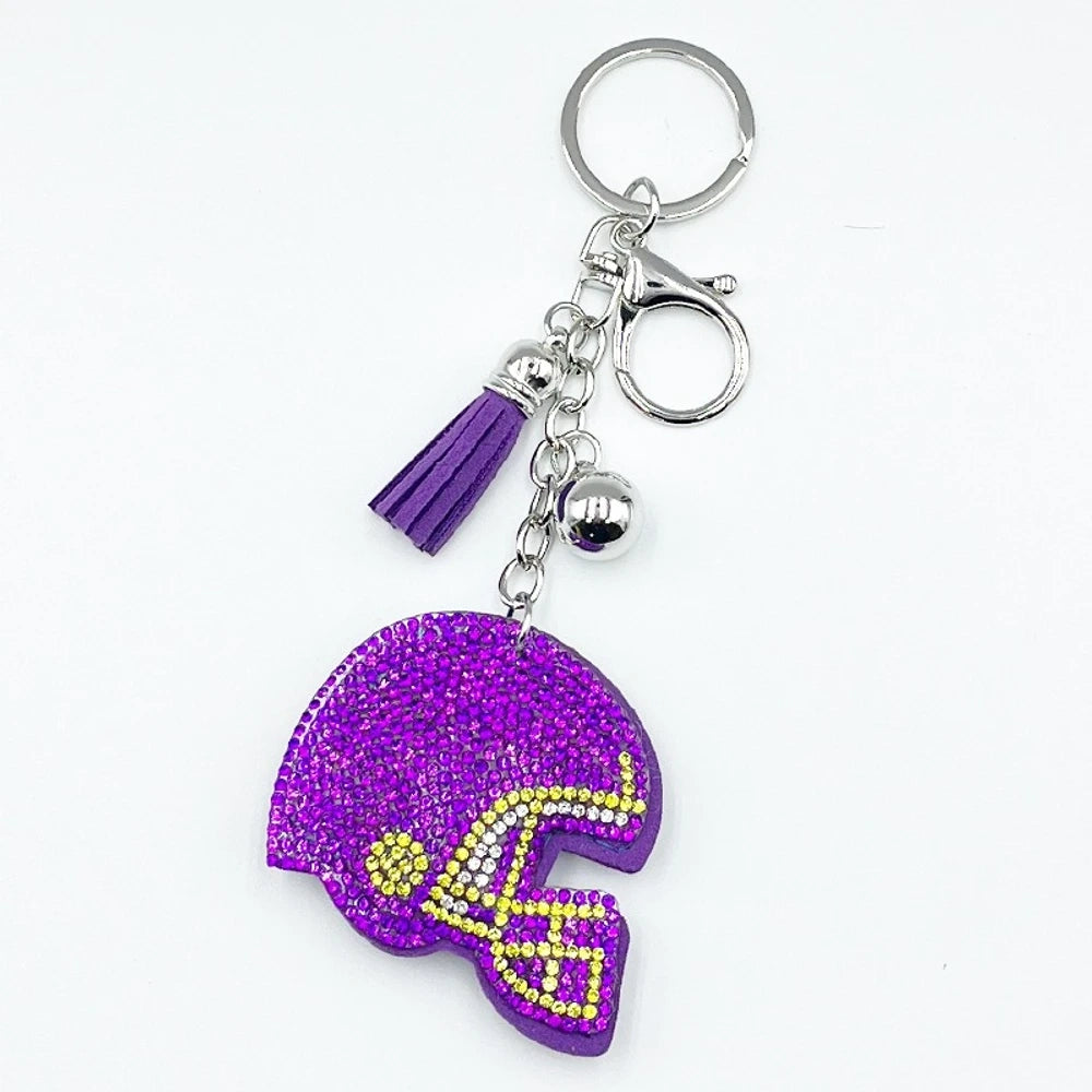 Five rhinestone-covered football helmet keychain charms in green, orange, black, blue, and purple with tassel and bell accents on silver key rings - Purple