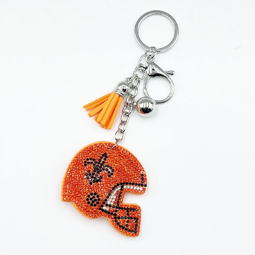 Five rhinestone-covered football helmet keychain charms in green, orange, black, blue, and purple with tassel and bell accents on silver key rings - Red