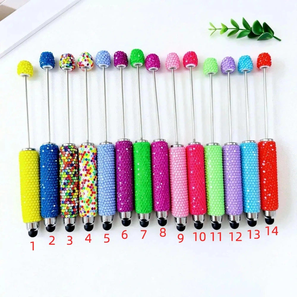 14 rhinestone glitter beadable stylus pens in assorted colors including yellow, blue, multicolor, lavender, purple, green, magenta, pink, hot pink, lime, light purple, lavender, teal, and red, numbered 1 through 14, with decorative beaded tops.