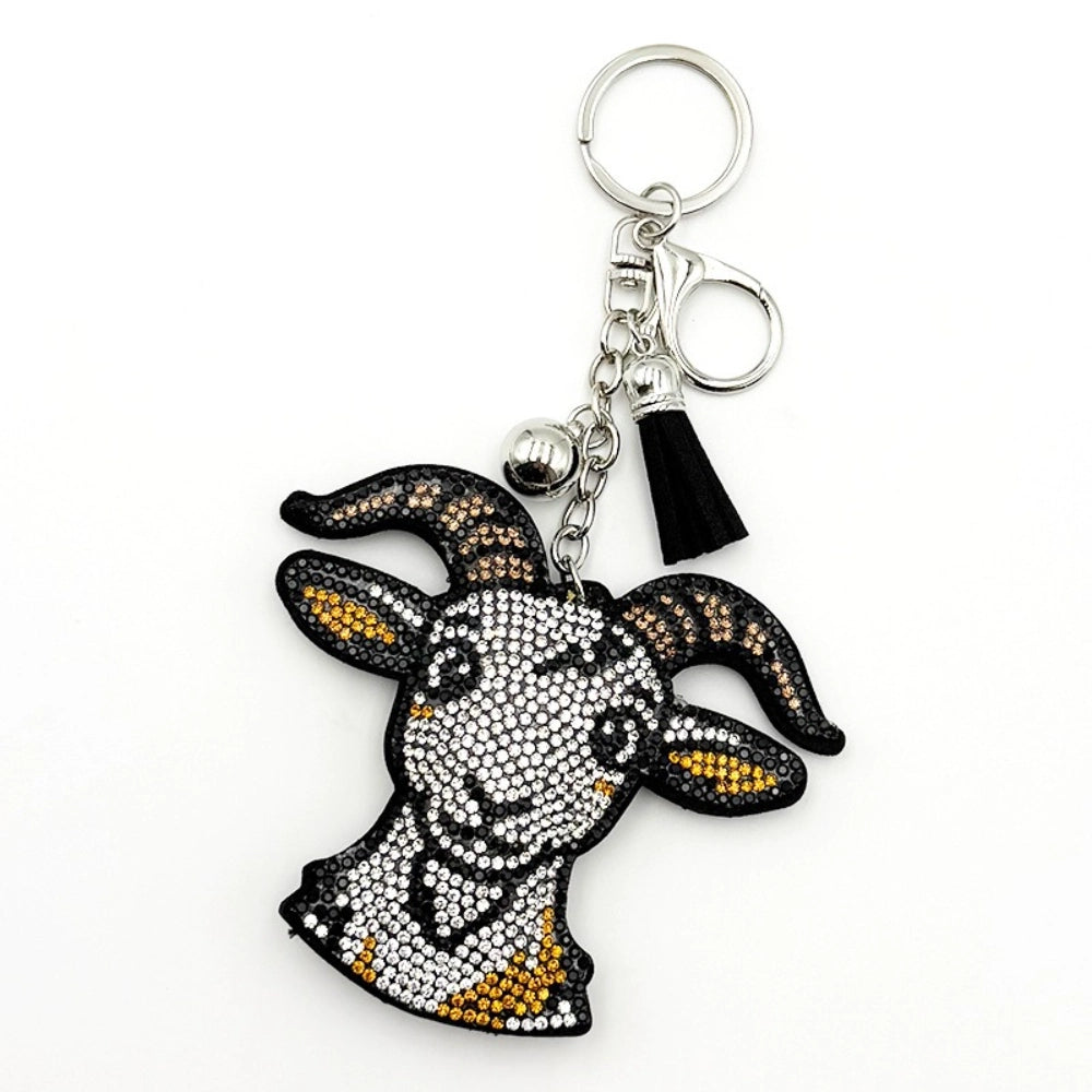 Rhinestone crystal goat head keychain charm with black and gold bling details, silver lobster clasp, silver ball bead, and black tassel pendant on white background.