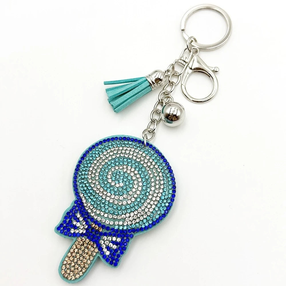 Two rhinestone-studded lollipop charm keychains in teal/blue and red/purple with tassels, silver rings, and bell accents for DIY jewelry making and keychains. - Blue