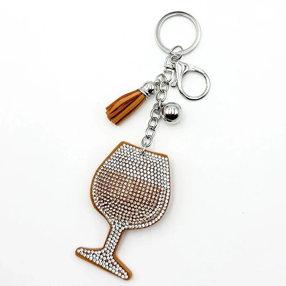 Four rhinestone-covered wine glass keychain charms in red, pink, blue, and black with matching tassels and silver bell accents on white background. - Khaki