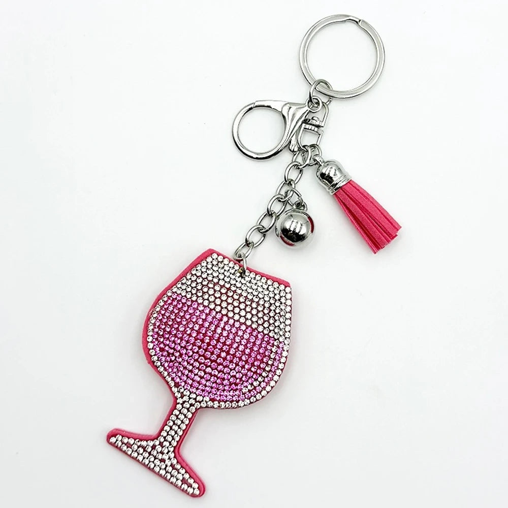 Four rhinestone-covered wine glass keychain charms in red, pink, blue, and black with matching tassels and silver bell accents on white background. - Pink