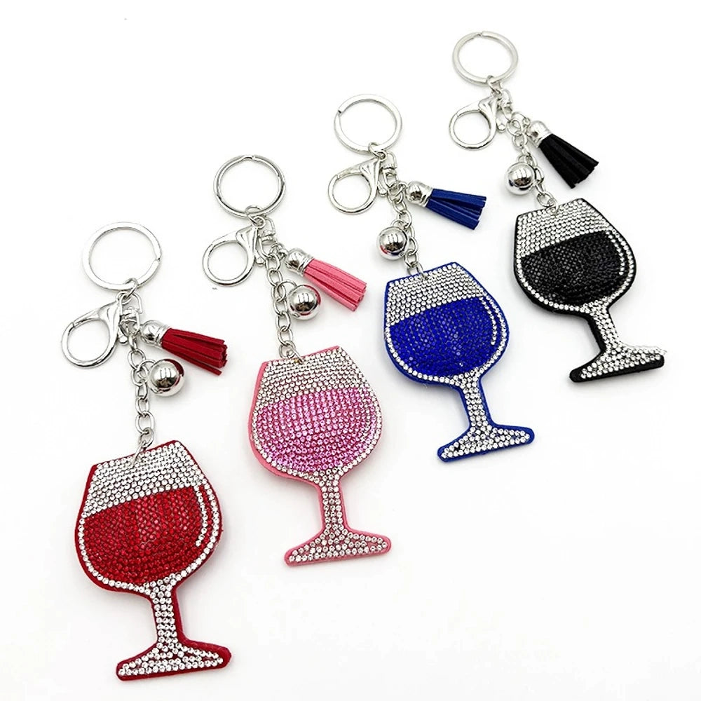 Four rhinestone-covered wine glass keychain charms in red, pink, blue, and black with matching tassels and silver bell accents on white background. - Random Mixed