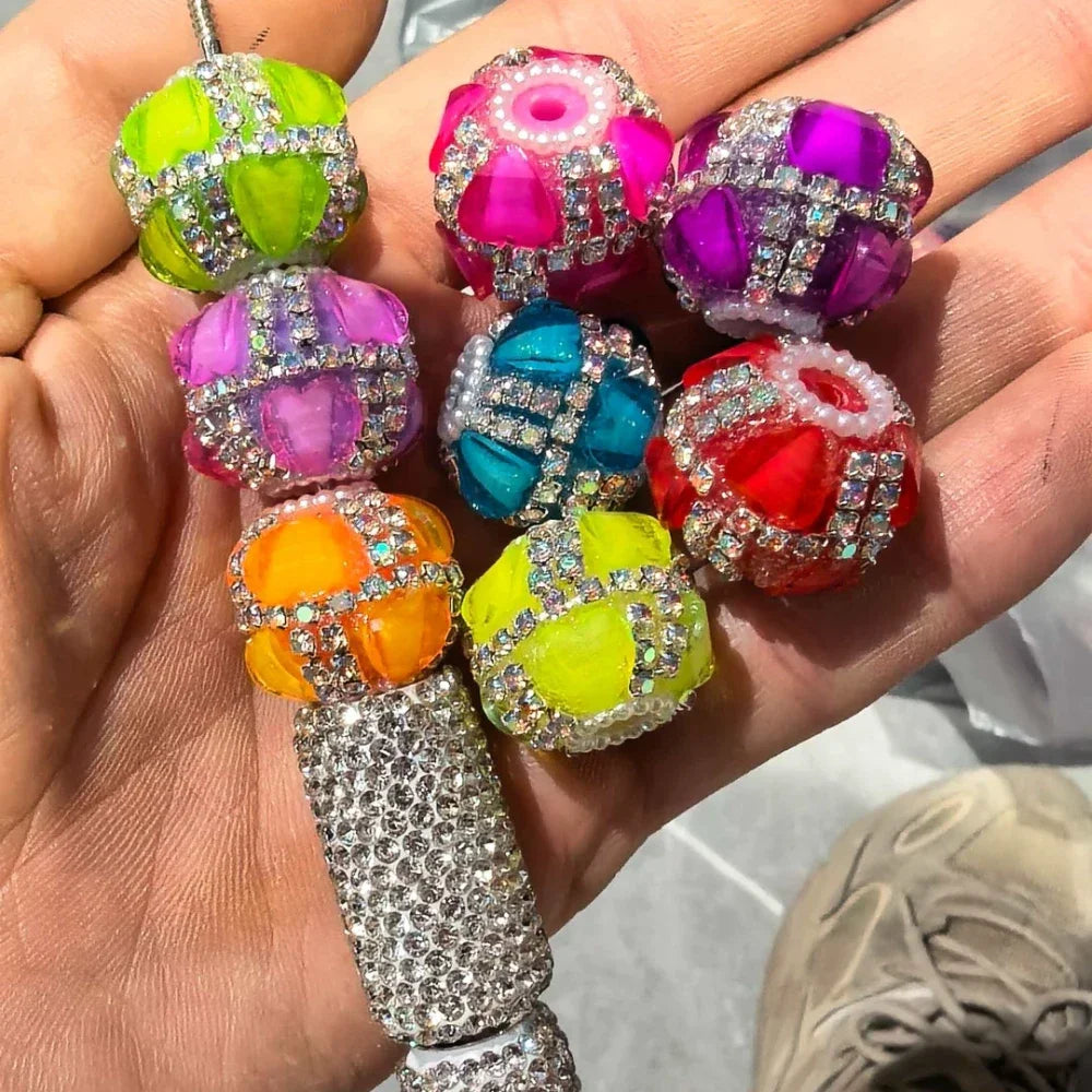Colorful rhinestone-wrapped neon acrylic round fancy beads in green, pink, purple, orange, teal, yellow, and red held in a hand, ideal for beadable pens, keychains, and DIY jewelry making.