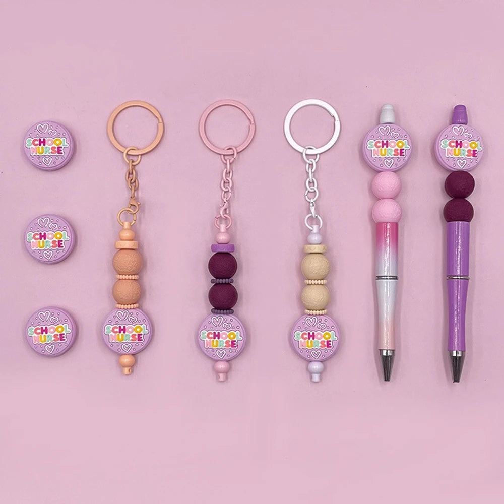 Purple School Nurse silicone focal bead shown on beadable pens and keychains with colorful text and heart details on a pink background
