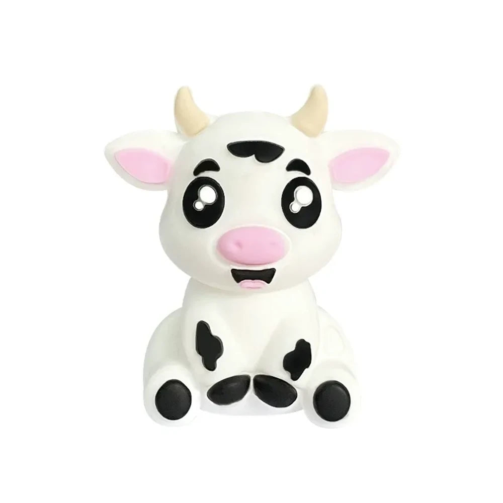 Set of 6 cute 3D baby cow silicone focal beads in white, tan, brown, and black color variants displayed on a miniature wooden bench against a yellow background. - White
