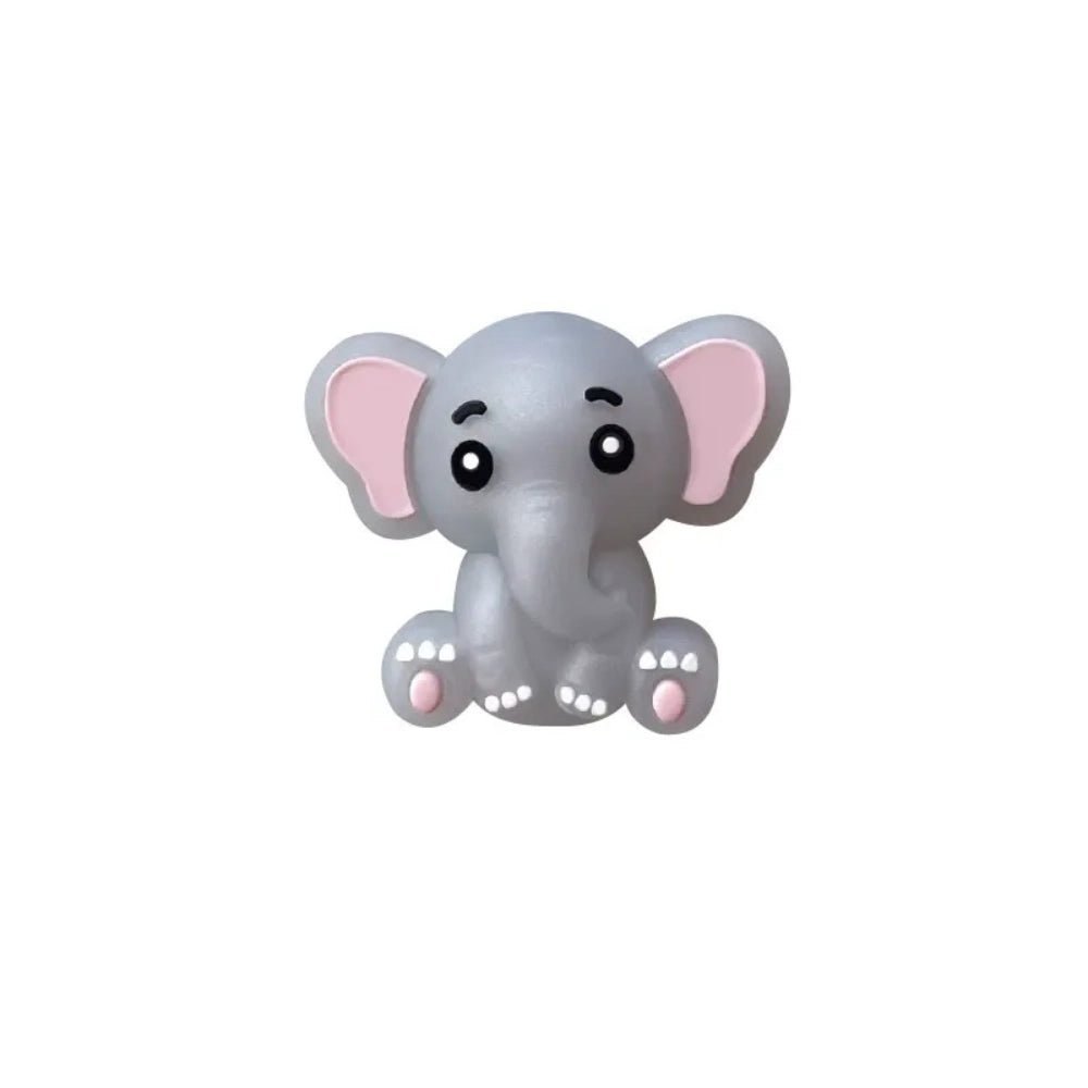 Five cute 3D baby elephant silicone focal beads in light gray, medium gray, dark gray, blue, and pink colors, sitting posed with pink inner ears and toenails, displayed on a white platform against a warm beige background. - Pearl Gray