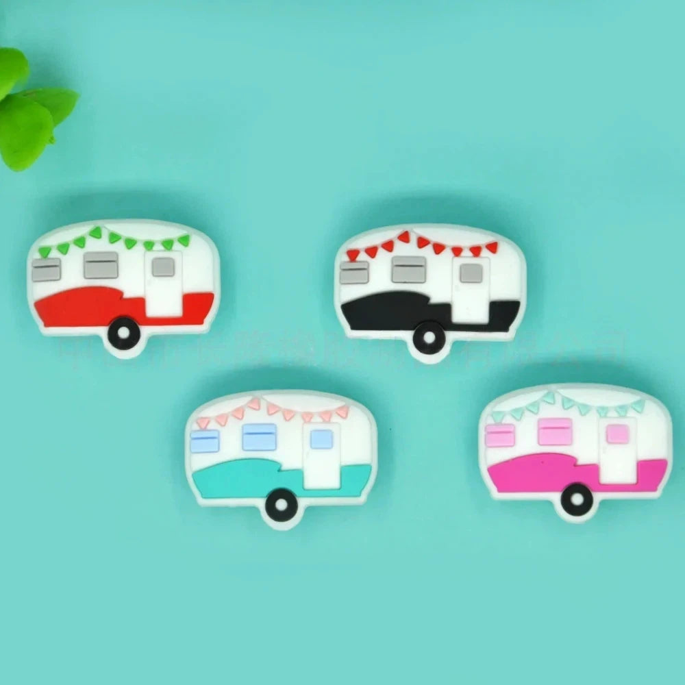 Four silicone camper trailer flatback focal beads in red, black, teal, and pink with bunting flag details on a teal background