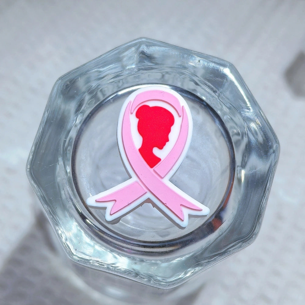 Silicone 3D focal beads in cancer awareness designs including pink and blue awareness ribbons, decorative bows, and 'Her Fight Is My Fight' charms displayed alongside completed beadable pens on a white textured background. - 3