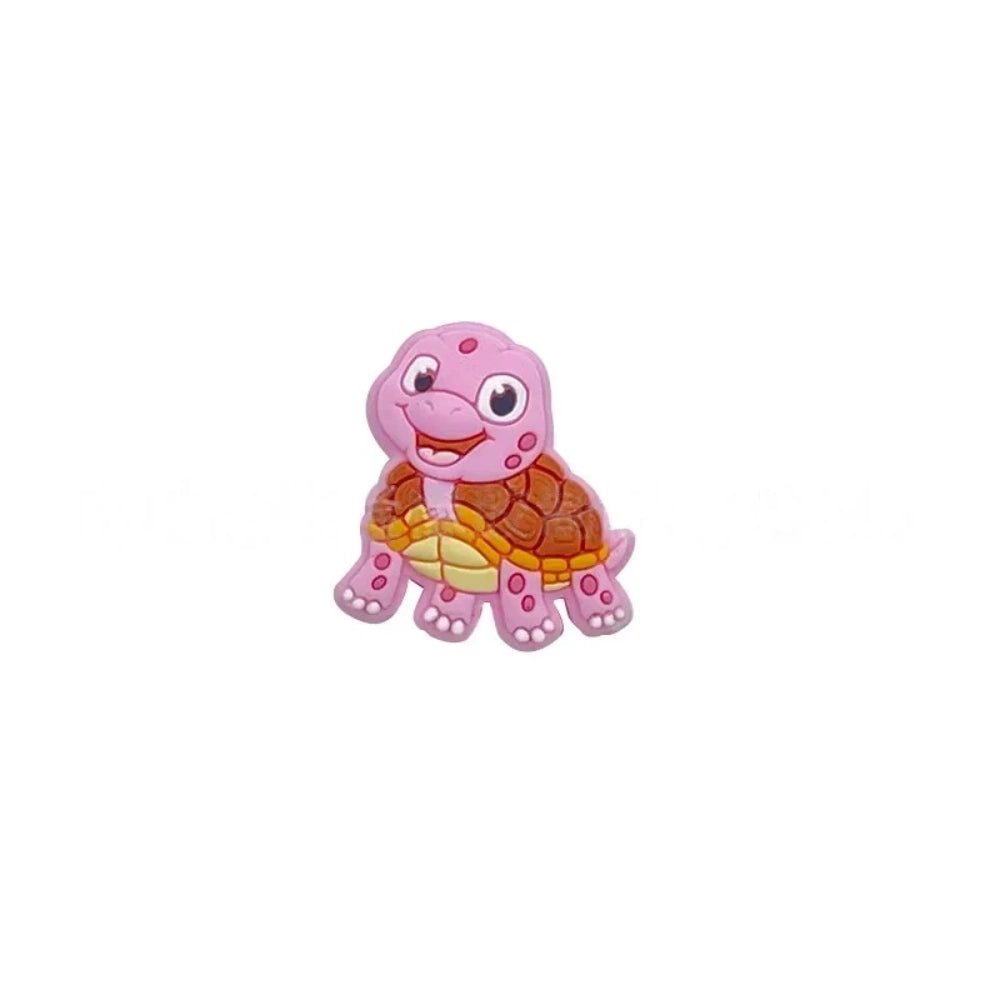 Cartoon turtle silicone focal beads in green, blue, yellow, and pink colors displayed on white pedestals against a pink background, available in large and small sizes for DIY crafts. - Pink