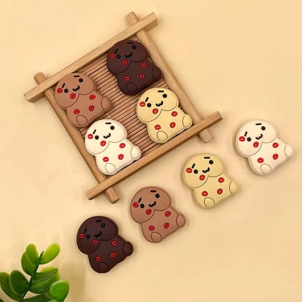 Seven silicone cookie bear focal beads in dark chocolate, milk chocolate, cream, and vanilla shades with red coffee bean accents and kawaii faces, displayed on a wooden tray and beige surface - Random Mixed