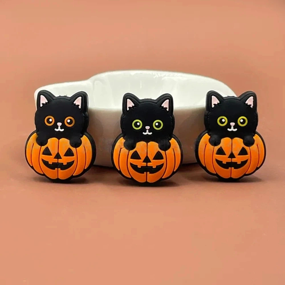 Three Halloween black cat sitting in jack-o-lantern pumpkin silicone focal beads displayed on a peach background, showing orange and black 3D character design. - Random Mixed