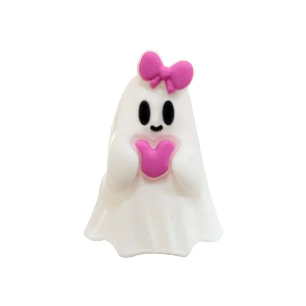 Three white Halloween ghost silicone focal beads – two holding jack-o-lantern pumpkins and one with a pink bow and heart – displayed in front of a white ceramic bowl on a beige surface. - 2