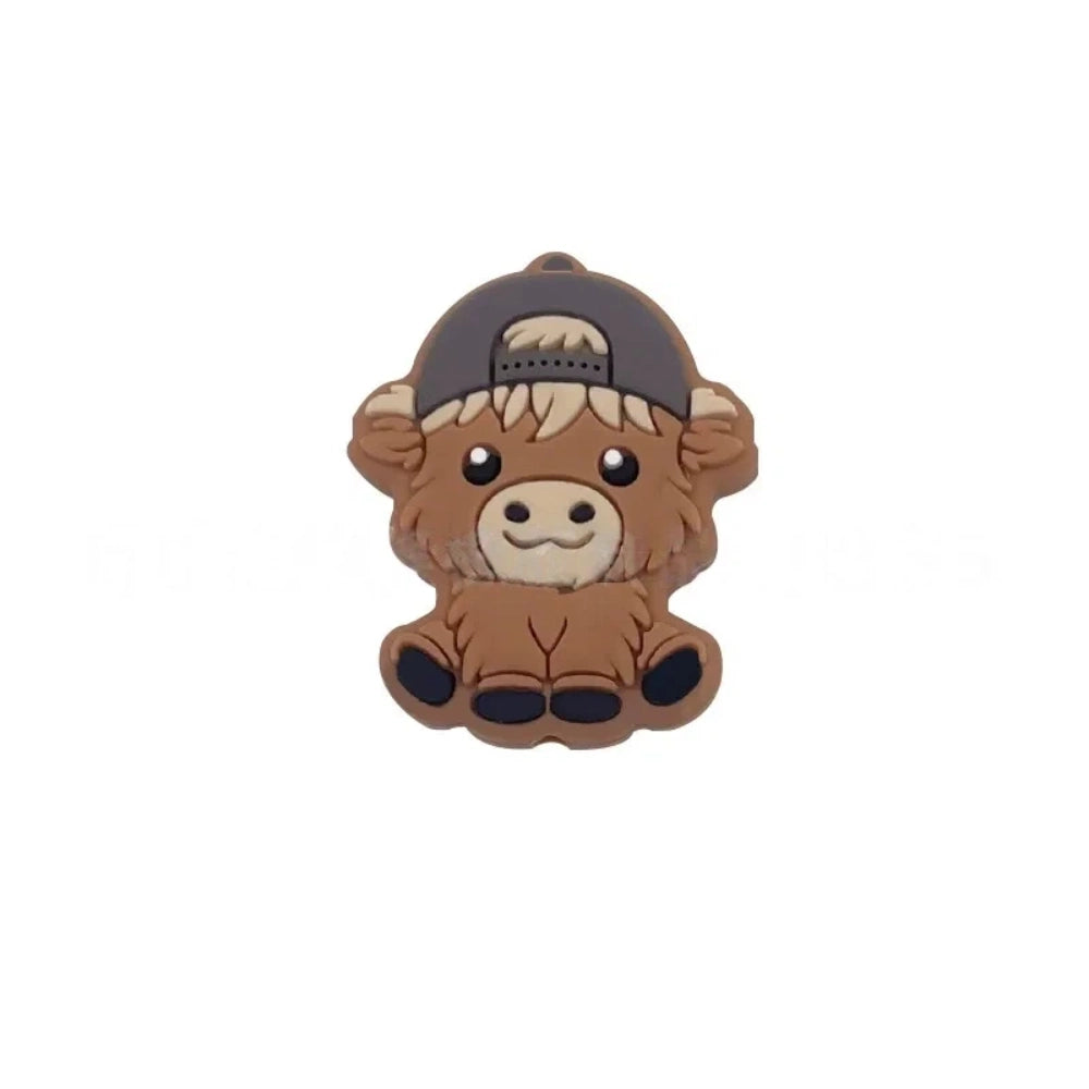 Six silicone Highland cow focal beads in brown – three wearing colorful baseball caps (blue, teal, gray) and three with bow accessories (mint, purple, pink) – crafting supplies for beadable pens, keychains, and badge reels. - Gray