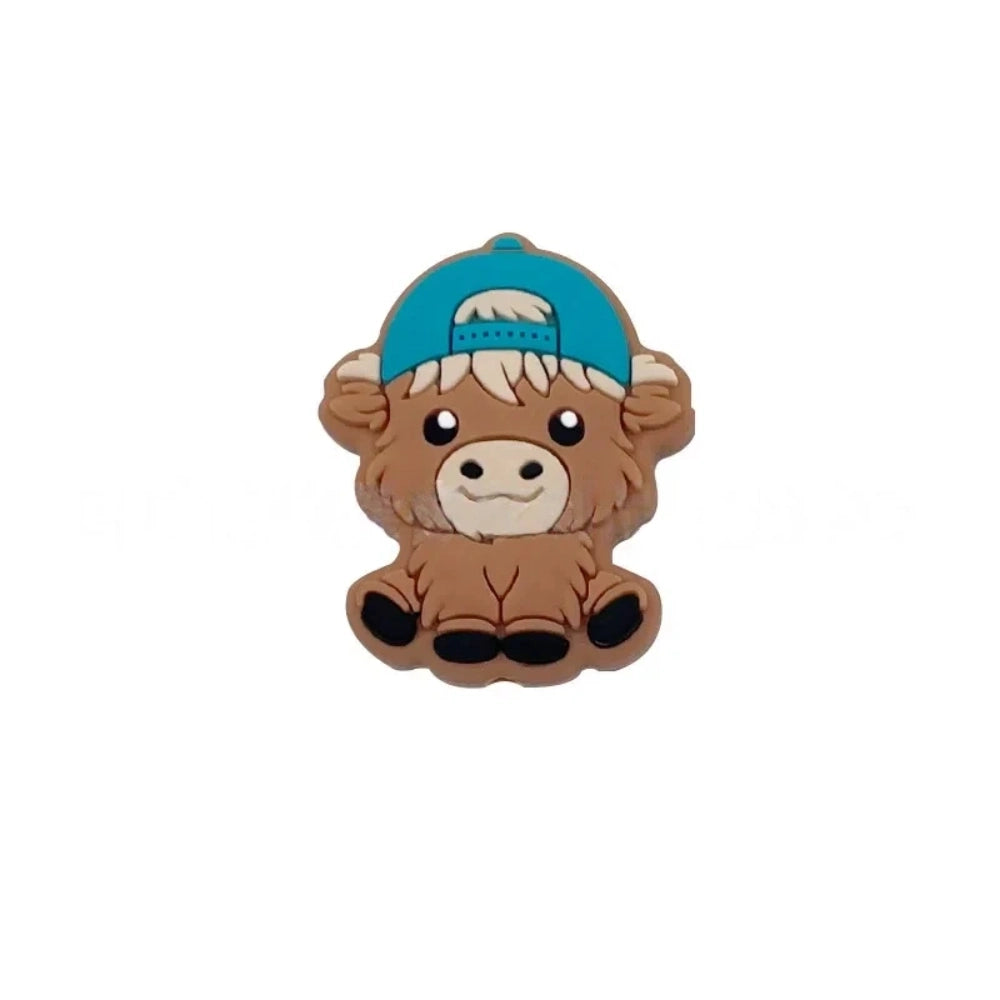 Six silicone Highland cow focal beads in brown – three wearing colorful baseball caps (blue, teal, gray) and three with bow accessories (mint, purple, pink) – crafting supplies for beadable pens, keychains, and badge reels. - Green