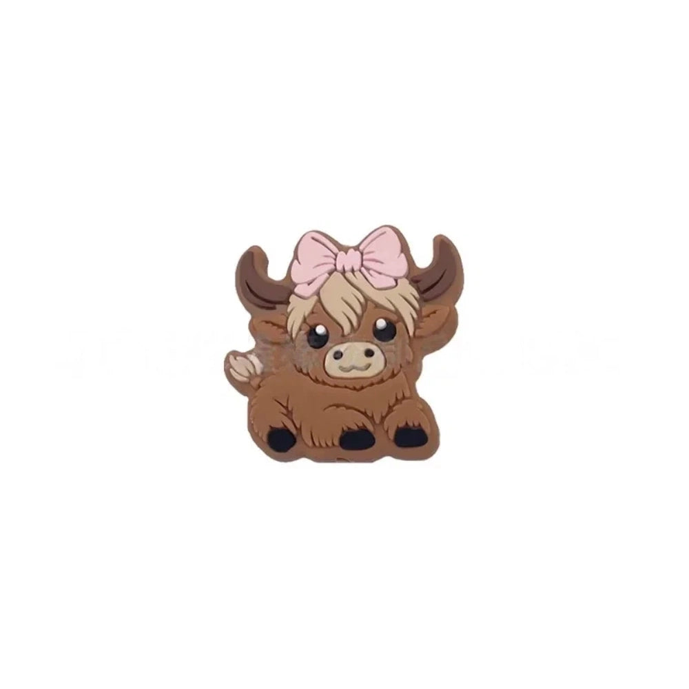 Six silicone Highland cow focal beads in brown – three wearing colorful baseball caps (blue, teal, gray) and three with bow accessories (mint, purple, pink) – crafting supplies for beadable pens, keychains, and badge reels. - Pink